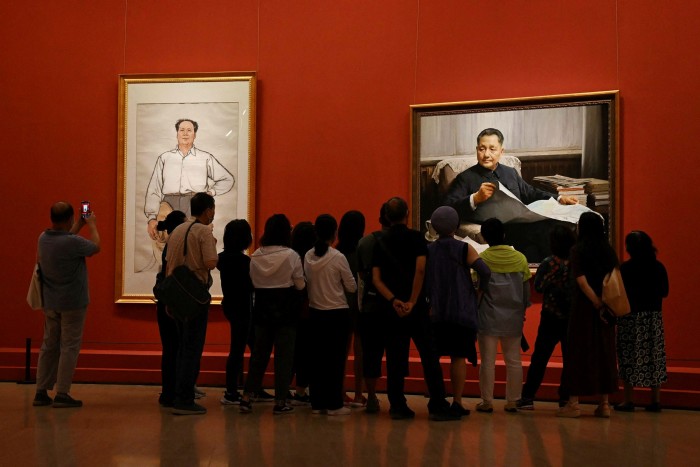 Visitors look at a paintings of  Mao Zedong (L) and Deng Xiaoping at an exhibition of art celebrating the 100th anniversary of the founding of the Communist party in Beijing 