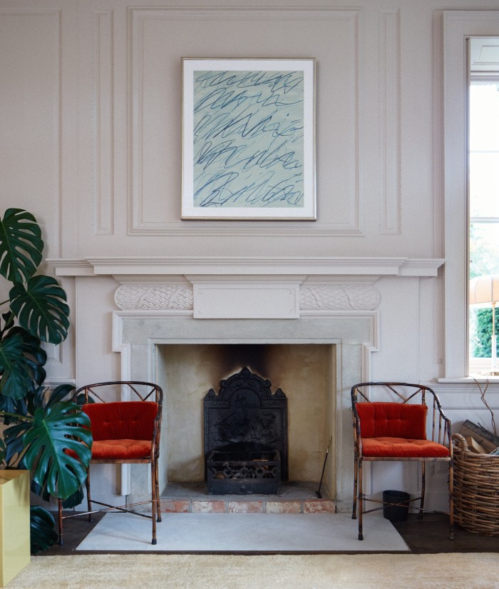A Cy Twombly print hangs above a pair of midcentury bamboo chairs