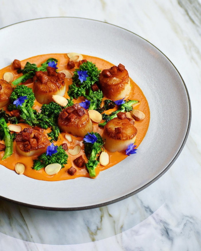 A bowl of scallops with grilled rapini, chorizo and romesco sauce at Hawksworth