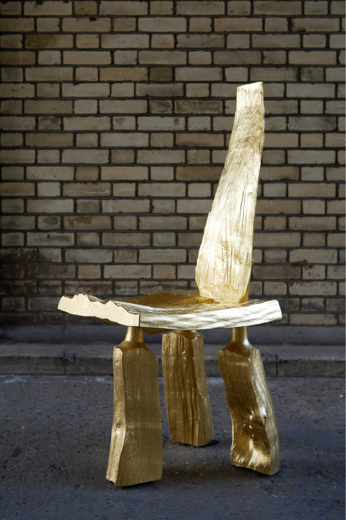 A golden rough-hewn three-legged chair