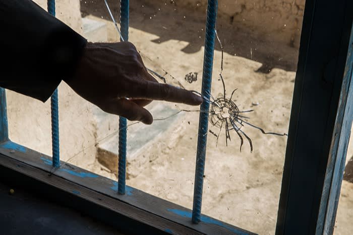 Sardar Mohammad, 46, points to the hole in the glass made by the bullet that killed his daughter Basmeen, 8, in the village of Dost Khol