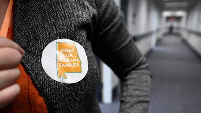 A person wears a sticker reading ‘Fight for Alabama families’