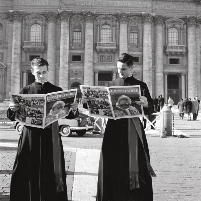 Two priests read L’Osservatore della Domenica outside St Peter’s Basilica in 1960