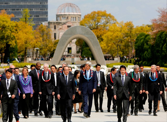 Government officials walking together after placing wreaths in front of the Memorial Cenotaph for the 1945 atomic bombing victims in the Peace Memorial Park