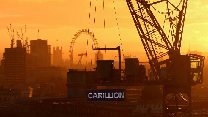 The sun sets behind a construction crane showing the branding of British construction company Carillion photographed on a building site in central London on January 15, 2018, with the skyline of the British capital in the background including the London Eye and the Houses of Parliament