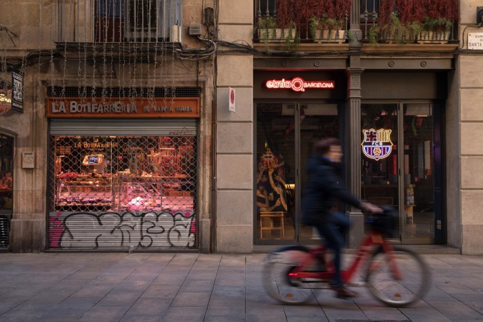 A person on a bicycle passes a shop with graffiti on its front 