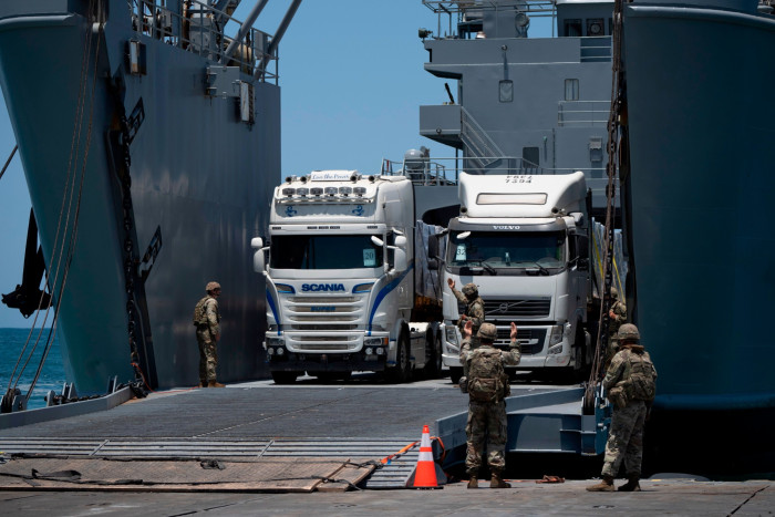Trucks loaded with humanitarian aid arrive at the US-built floating pier Trident before reaching the beach on the coast of the Gaza Strip