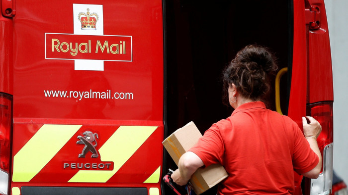 A postal worker getting parcels from a Royal Mail van