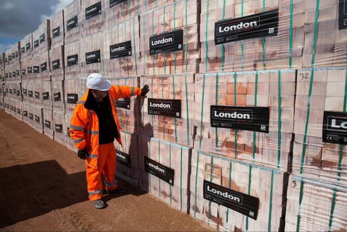 A worker inspects stacks of finished London bricks at the Forterra brickworks near Peterborough, UK