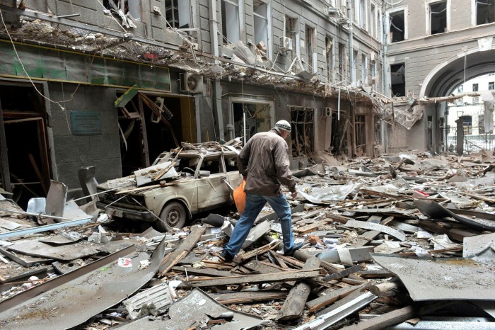 A man in the Ukrainian city of Kharkiv walks through rubble after Russian shelling destroyed buildings. Russia is using air strikes, heavy artillery and armoured vehicles to try to pound its neighbour into submission