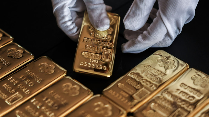 An employee handles one kilogram gold bullion at the YLG Bullion International headquarters in Bangkok