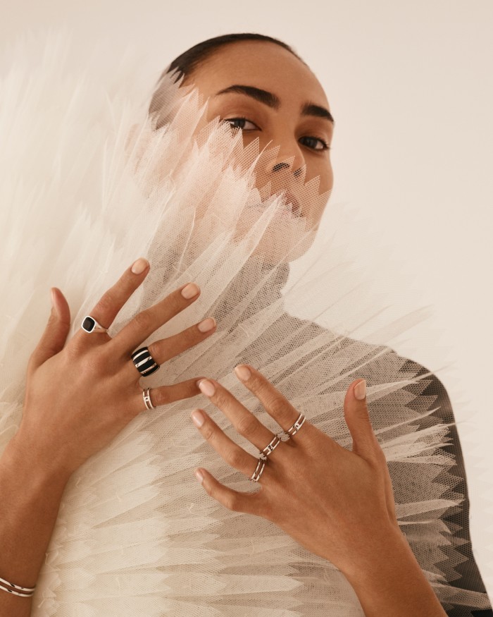 A model wears a recycled gold and wood Isadora ring (right hand) and silver Breeze ring (left hand)