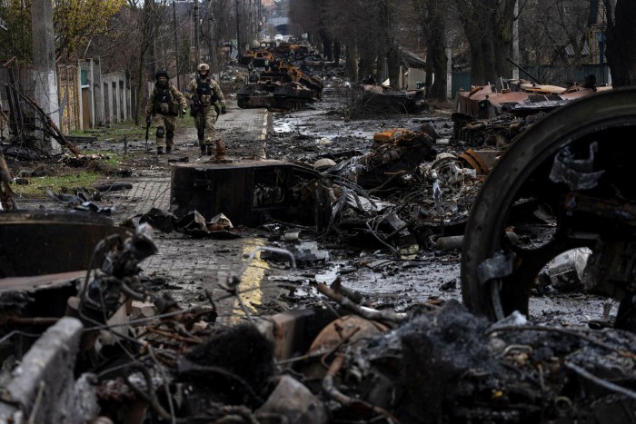 Soldiers walk through destroyed Russian tanks in Bucha, close to Kyiv, on Sunday