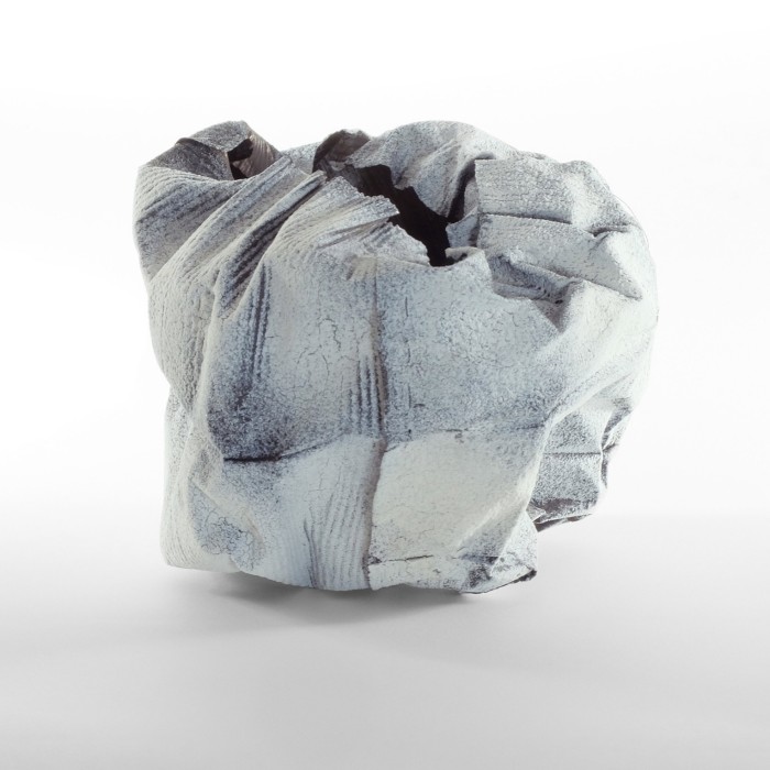A vase made from crumpled white metal with blue traces
