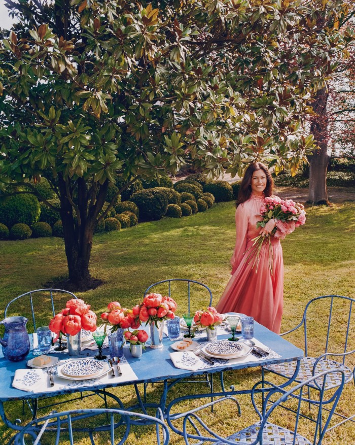 De Castellane in the garden. On the table are Dior Maison Blue Mizza water glasses, £160 each, carafe, £370, dinner plates, £130 each, dessert plates, £100 each, bread plates, £75 each, and placemat and napkin set, £430. Riviera Savana knives, forks and spoons, all £110 each