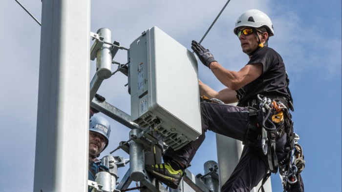 Technicians mount a 5G antenna on a mast