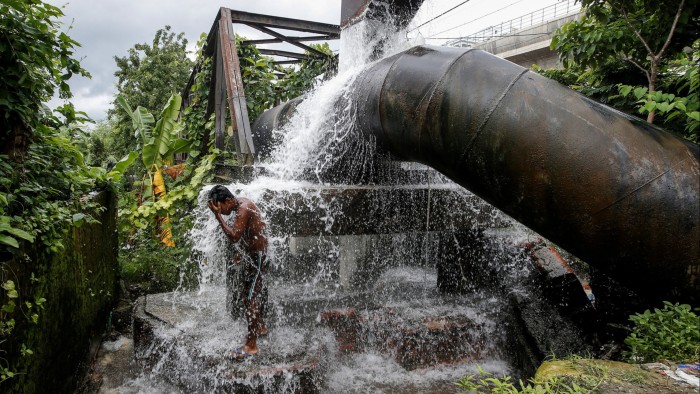 A man baths in water from a broken drinking water pipe in Kolkata, India