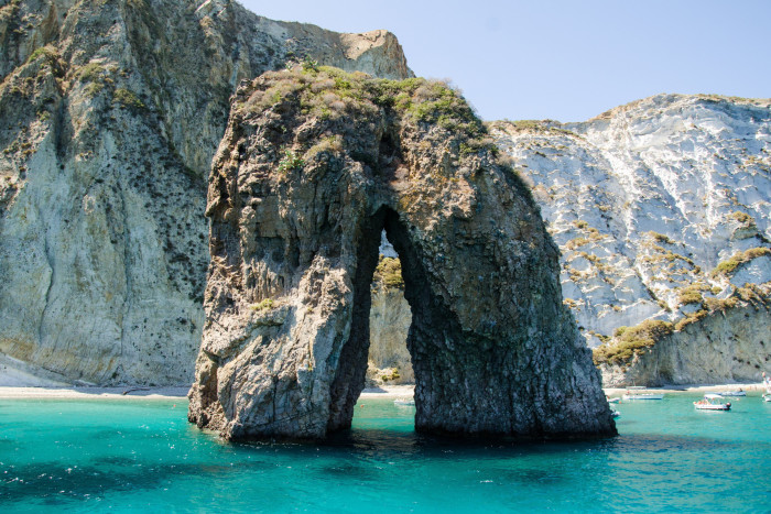 A natural arch called Scoglio del Parroco (“the priest’s rock”) in the sea off the island of Ponza. Behind it are white cliffs 