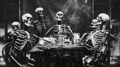Six skeletons smoking around the dinner table, circa 1865. (Photo by London Stereoscopic Company/Hulton Archive/Getty Images)