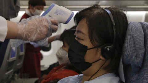 Stewardesses take temperatures of passengers as a preventive measure for the coronavirus on an Air China flight from Melbourne to Beijing before it land at Beijing Capital International Airport in China, Tuesday, Feb. 4, 2020. China said Tuesday the number of infections from a new virus surpassed 20,000 as medical workers and patients arrived at a new hospital and President Xi Jinping said &quot;we have launched a people's war of prevention of the epidemic.&quot; (AP Photo/Andy Wong)