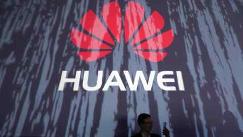 An attendee holds a smartphone in front of a Huawei Technologies Co. logo at the launch event of their P9 smartphone in London, U.K., on Wednesday, April 6, 2016. Huawei's profit surged 33 percent in 2015 after China's largest maker of telecommunications gear grabbed market share with premium smartphones and mobile carriers expanded their high-speed networks globally. Photographer: Chris Ratcliffe/Bloomberg