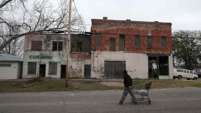 A pedestrian pulls a shopping cart by vacant buildings on March 6, 2015 in Selma, Alabama