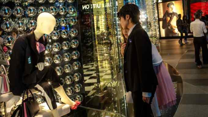 People looks at a store window of a Prada SpA luxury fashion store on Orchard Road in Singapore, on Sunday, Dec. 16, 2016. Shopping has overtaken gambling as the biggest earner in Singapore's tourism industry for the first time since 2012, surging 44 percent in the six months through June from a year ago, official data show. Photographer: Sanjit Das/Bloomberg