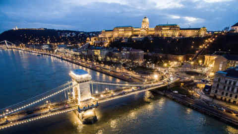 Buda Castle stands illuminated at night as vehicles travel accross the Chain Bridge in Budapest, Hungary, on Tuesday, Feb. 23, 2016. The Hungarian central bank may ease monetary conditions further as they seek to combat below-forecast inflation and limit an economic slowdown, policy makers said, after leaving the benchmark interest rate unchanged for a seventh month. Photographer: Akos Stiller/Bloomberg