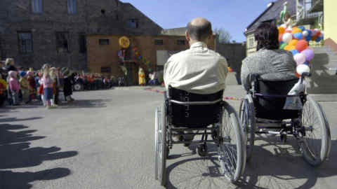 two persons in wheelchairs
