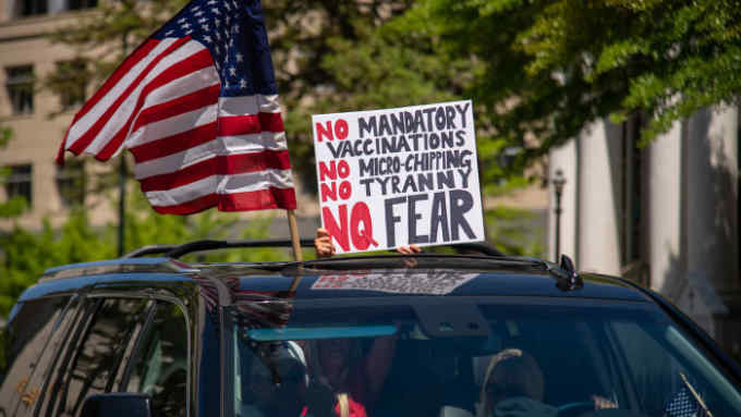 A woman holds a sign voicing various conspiracy theories believed by QAnon followers out of the sunroof of a car at the &quot;Reopen Virginia&quot; protest in Richmond on April 22nd, 2020. Three Percenters are a movement that advocates for constitutional rights, and takes its name from the belief that only three percent of America took up arms against the British during the Revolutionary War. (Photo by Matthew Rodier/Sipa USA)