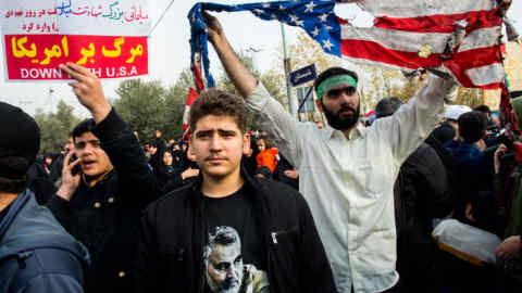 Protesters hold up a damaged U.S. flag and anti-USA banners during a demonstration following the U.S. airstrike in Iraq which killed a top Iranian commander, in Tehran, Iran, on Friday, Jan. 3, 2020. Qassem Soleimani, who led proxy militias that extended Iran’s power across the Middle East, was killed in a drone attack in Baghdad authorized by President Trump, the Defense Department said in a statement late Thursday. Photographer: Ali Mohammadi/Bloomberg