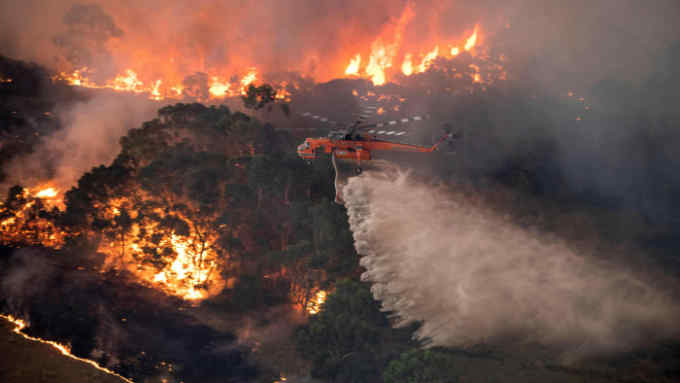 A handout photo taken and received on December 31, 2019 from the State Government of Victoria shows a helicopter fighting a bushfire near Bairnsdale in Victoria's East Gippsland region. - Thousands of holidaymakers and locals were forced to flee to beaches in fire-ravaged southeast Australia on December 31, as blazes ripped through popular tourist areas leaving no escape by land. (Photo by Handout / STATE GOVERNMENT OF VICTORIA / AFP) / RESTRICTED TO EDITORIAL USE - MANDATORY CREDIT &quot;AFP PHOTO / STATE GOVERNMENT OF VICTORIA&quot; - NO MARKETING NO ADVERTISING CAMPAIGNS - DISTRIBUTED AS A SERVICE TO CLIENTS (Photo by HANDOUT/STATE GOVERNMENT OF VICTORIA/AFP via Getty Images)