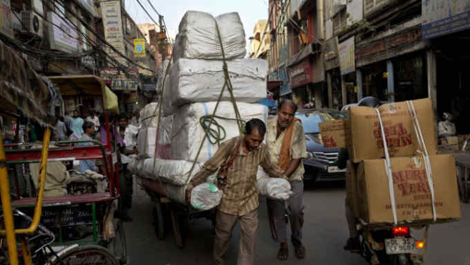A Indian laborer pulls a cart heavily loaded with goods while others assist him as they make their way through a crowded street in the old city area of New Delhi, India, Thursday, Aug. 21, 2014. (AP Photo/Bernat Armangue)