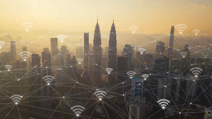 Digital network connection lines and wifi icons with Kuala Lumpur Downtown, Malaysia. Financial district in smart city in technology concept. Skyscraper and high-rise buildings at sunset