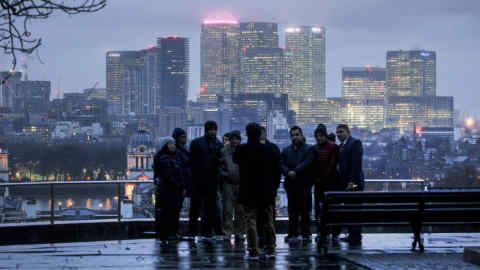 Visitors look out from Greenwich park against a backdrop of offices of global financial institutions, including Citigroup Inc., State Street Corp., Barclays Plc, HSBC Holdings Plc, and the commercial office block No. 1 Canada Square, in Canary Wharf in London, U.K., on Monday, Dec. 12, 2016. Credit Suisse Group AG is planning to sublease space in London’s Canary Wharf district after cutting staff and squeezing costs, according to two people with knowledge of the plan. Photographer: Simon Dawson/Bloomberg