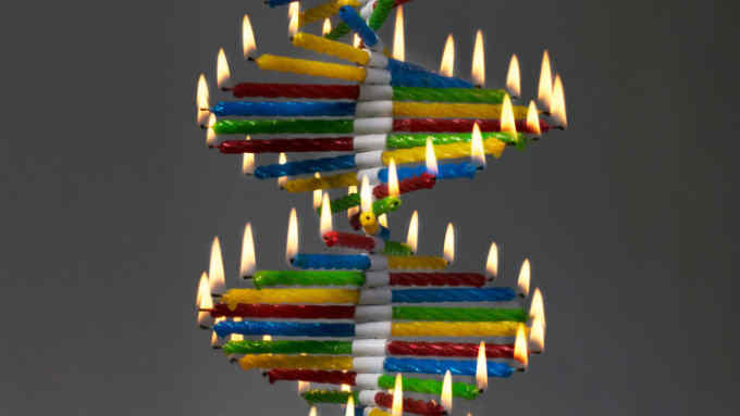 Lighted birthday candles stacked in a DNA genome-like sequence