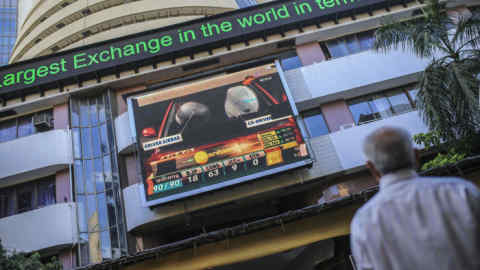 A man stands in front of an electronic ticker board showing stock information figures outside the Bombay Stock Exchange (BSE) in Mumbai, India, on Tuesday, Dec. 11, 2018
