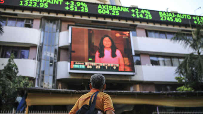 A pedestrian look towards a screen and an electronic ticker board showing stock figures outside the Bombay Stock Exchange (BSE) building in Mumbai, India, on Tuesday, Dec. 11, 2018. India’s new central bank governor has a list of challenges to face as he takes office: from fixing a banking crisis to convincing investors of the institution’s autonomy. Photographer: Dhiraj Singh/Bloomberg