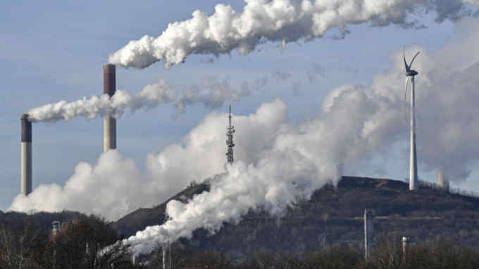 A Uniper coal-fired power plant and BP refinery steam beside a wind generator in Gelsenkirchen, Germany, Thursday, Jan. 16, 2020. The German government says officials have agreed on a plan to shut down the nation's coal-fired power plants by the mid to late 2030s. (AP Photo/Martin Meissner)