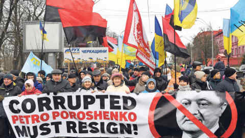 People hold a banner depicting the crossed out Ukrainian President Petro Poroshenko and with the signing reading &quot;Corrupted Petro Poroshenko nust resign!&quot; during a protest march calling for his impeachment which headed Former Georgian president in Kiev on February 4,2018. / AFP PHOTO / Sergei SUPINSKY (Photo credit should read SERGEI SUPINSKY/AFP/Getty Images)