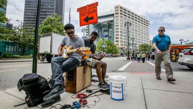Street performers play guitars near Campus Martius Park in Detroit, Michigan, U.S., on Thursday, June 22, 2017. To lure more young talent straight out of school, Detroit is giving itself a full-on Silicon Valley makeover. General Motors Co. is spending $1 billion renovating its 60-year-old Tech Center in a northern suburb. Photographer: Anthony Lanzilote/Bloomberg