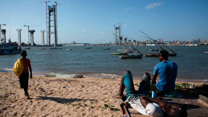 People relax on a beach near the construction site of the Maputo-Catembe Bridge, which will be the longest suspension bridge in Africa once completed, in Maputo on February 10, 2017. / AFP PHOTO / JOHN WESSELS        (Photo credit should read JOHN WESSELS/AFP/Getty Images)