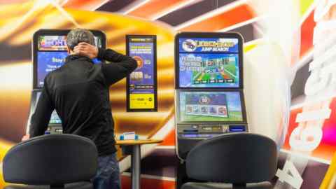 GG705P Mature man using fixed odds Roulette machine in Bookmakers. England, UK