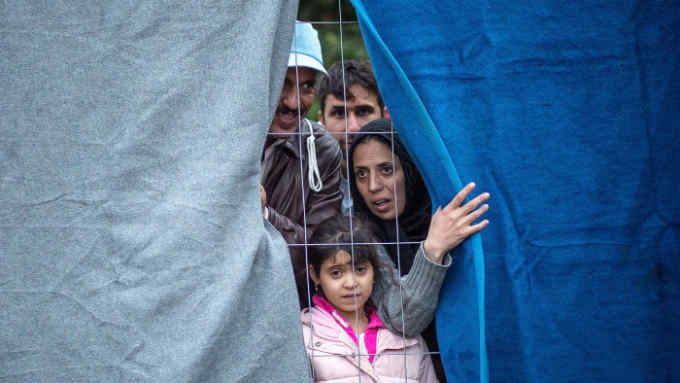 Migrants look through the fence as they wait to cross the Slovenia-Austrian border in Spielfeld, Austria, on October 22, 2015.
