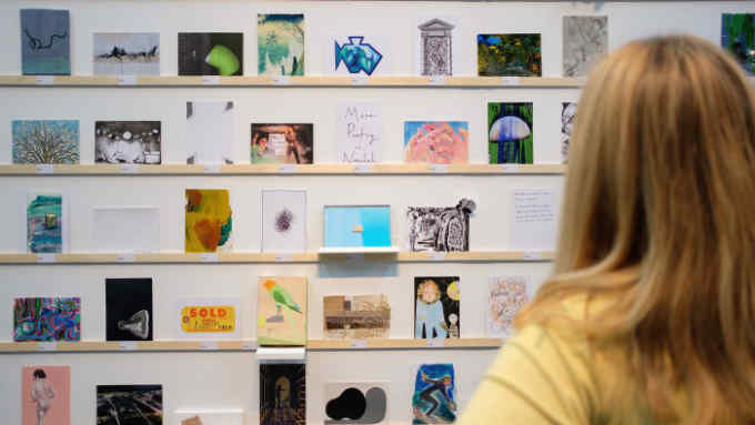 LONDON, ENGLAND - SEPTEMBER 08:  A woman looks at some of the postcards displayed in the RCA Secret Postcard fundraising exhibition at the Royal College of Art on September 8, 2017 in London, England.  The annual event sees artists creating work on postcards which are then displayed anonymously. The customer only finds out the artist upon purchase. Selling for £55 each, artists such as Peter Blake, Zandra Rhodes, Paul Smith and Tracey Emin have donated their work to this years sale.  (Photo by Leon Neal/Getty Images)