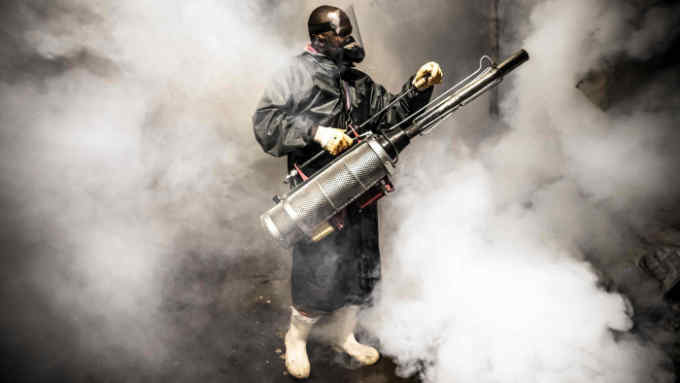 TOPSHOT - A member of a privately-funded NGO working with county officials wearing protective gear fumigates and disinfects on April 15, 2020, during the dusk-to-dawn curfew imposed by the Kenyan Government, the streets and the stalls at Parklands City Park Market in Nairobi to help curb the spread of the COVID-19 coronavirus. - With a current official number of 225 confirmed coronavirus cases, Kenya has so far cordoned off the capital and parts of its coastline and imposed a curfew and other social distancing measures as part of the country efforts to control the spread of the virus. (Photo by LUIS TATO / AFP) (Photo by LUIS TATO/AFP via Getty Images)