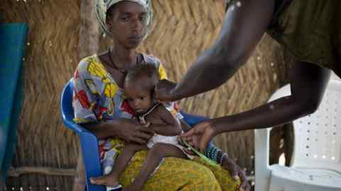 In this photograph taken on October 2, 2017, Sira Bah (C) an 16 month-old child, is measured by an health worker to identify signs of malnutrition in Siratogo. / AFP PHOTO / COLIN DELFOSSE (Photo credit should read COLIN DELFOSSE/AFP/Getty Images)