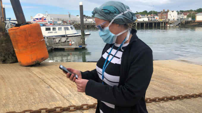 UK National Health Service employee Anni Adams looks at new NHS app to trace contacts with people potentially infected with the coronavirus disease (COVID-19) being trialled on Isle of Wight, Britain, May 5, 2020. Picture taken May 5, 2020. REUTERS/Isla Binnie
