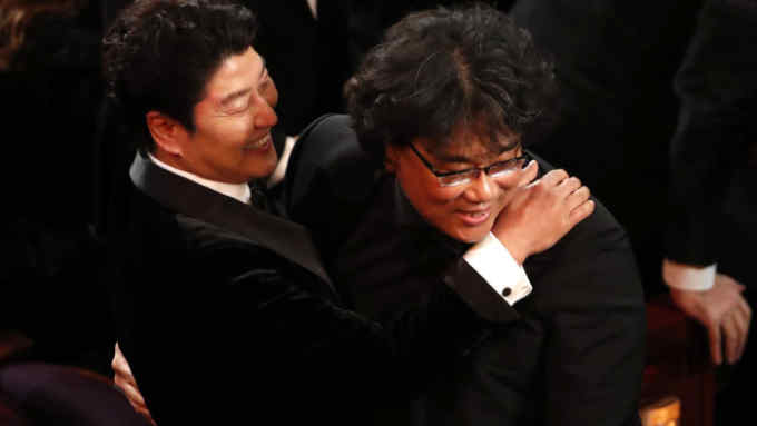 'Parasite' director Bong Joon-ho is hugged by Song Kang-ho, one of the film's stars, at the Oscars ceremony