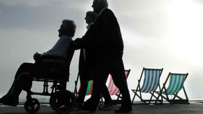 Pensioners walking past Empty deckchairs by beach Southend on sea